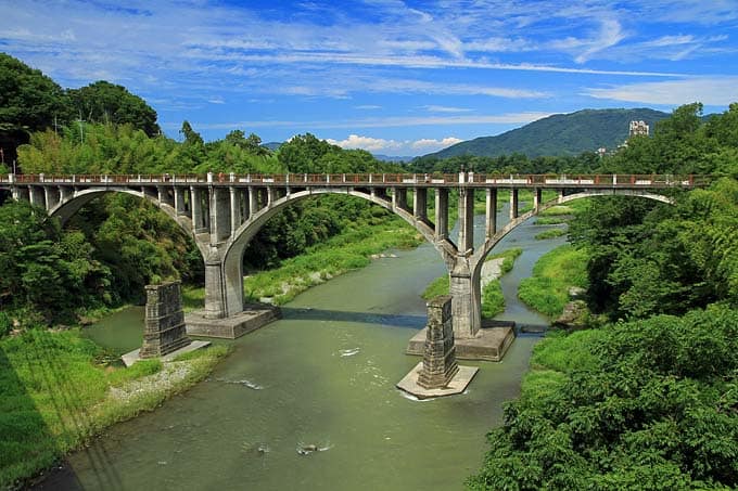 舊秩父橋夏季綠意景觀,橋身拱形結構與荒川河谷
