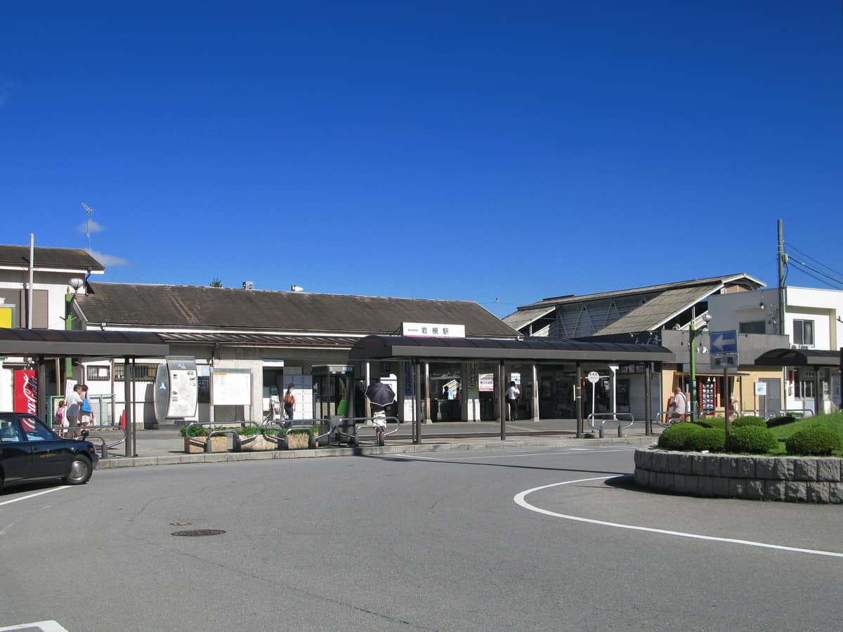 The exterior of Iwatsuki Station and its front plaza, under a clear blue sky