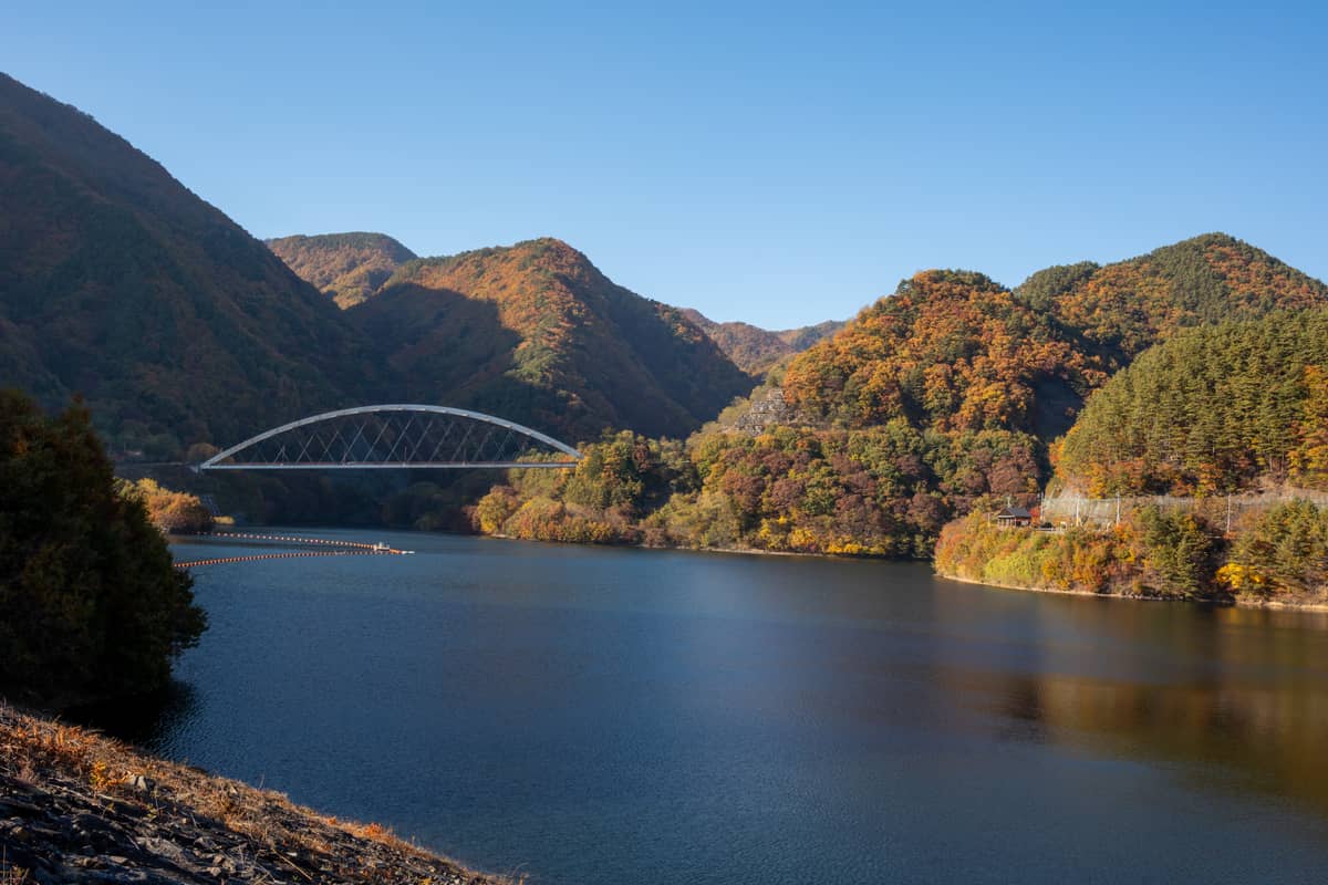 瑞牆湖秋季景色,拱形鐵橋跨越湖面、周邊山林楓紅