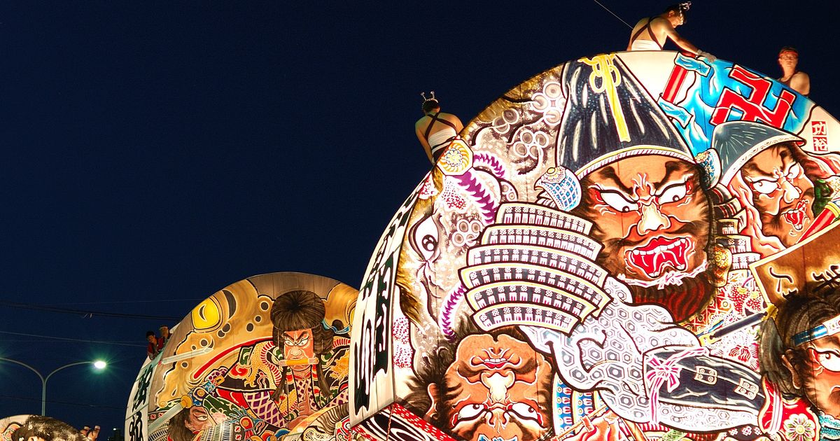 Two large fan-shaped Hirosaki Neputa floats painted with warrior scenes moving along a night street, the hauling crew and onlookers along the bottom edge
