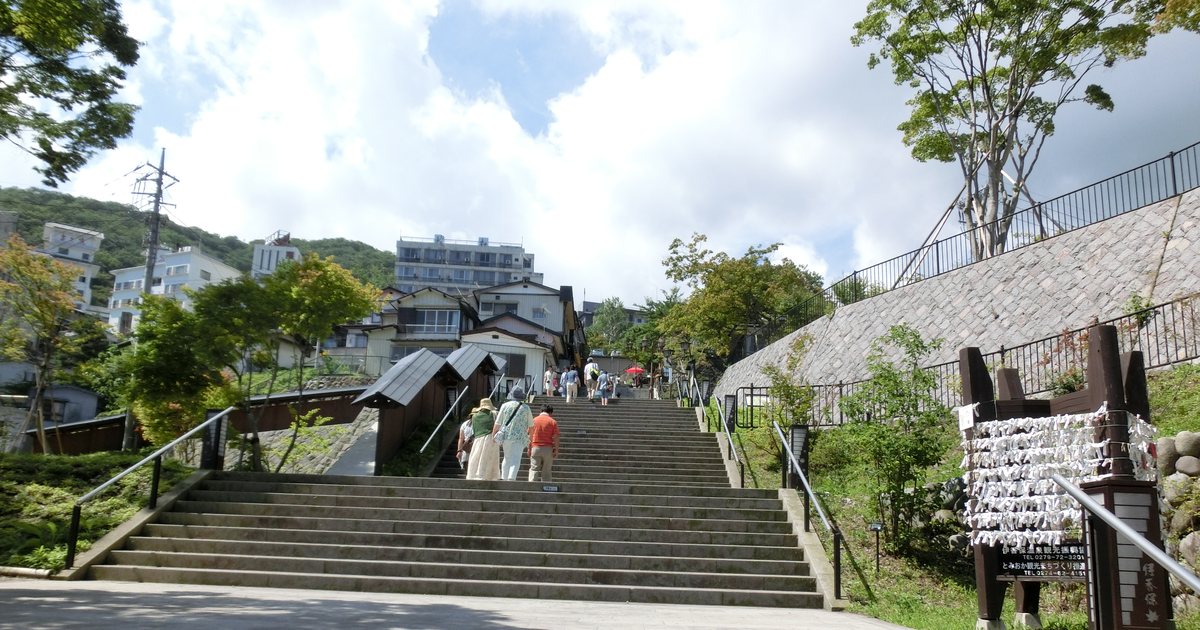 伊香保石段街：寬闊的石階沿著山坡往上，兩側是綠樹與依山而建的溫泉旅館