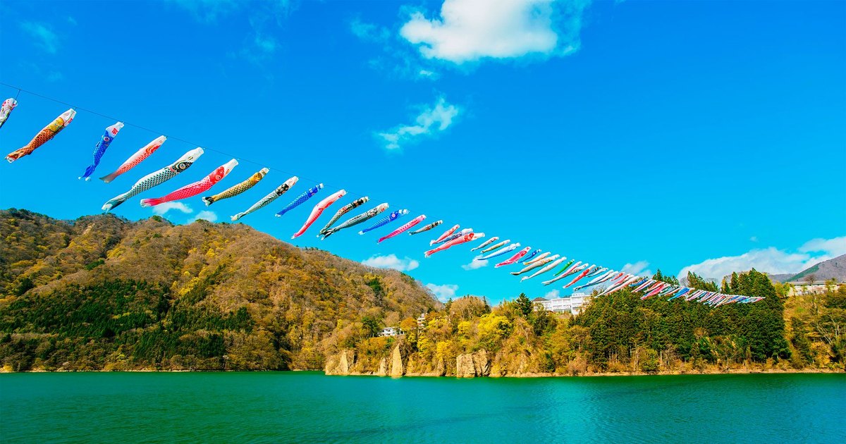 群馬赤谷湖上空拉起一長排彩色鯉魚旗，橫越湖面與早春的山坡