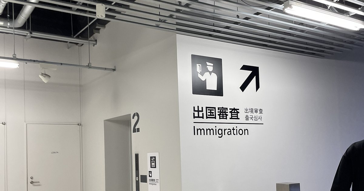 成田機場第 3 航廈白牆上的出國審查指標:審查官圖示、右上箭頭,寫著「出国審査 Immigration」與中韓文