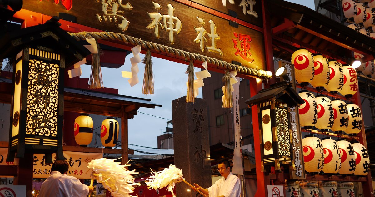 The gate of Otori Shrine in Asakusa during Tori no Ichi, hung with rows of lanterns reading “Tori no Ichi” as priests wave purification wands