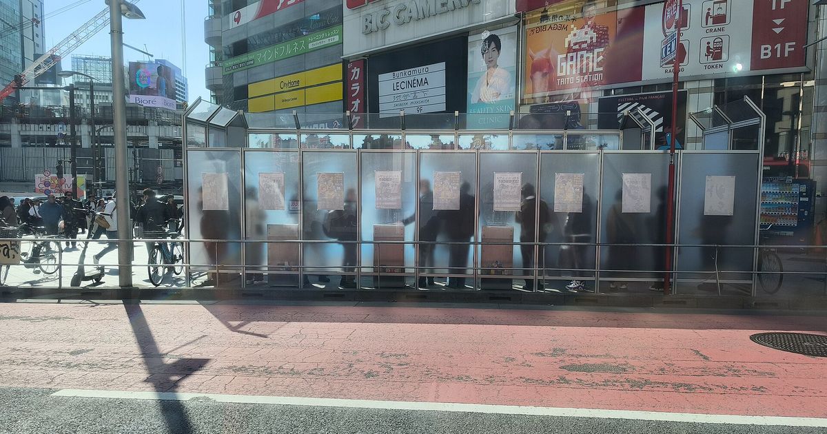 A panel-enclosed designated smoking area on a Shibuya street, with smokers inside and pedestrians and cyclists passing on the pavement