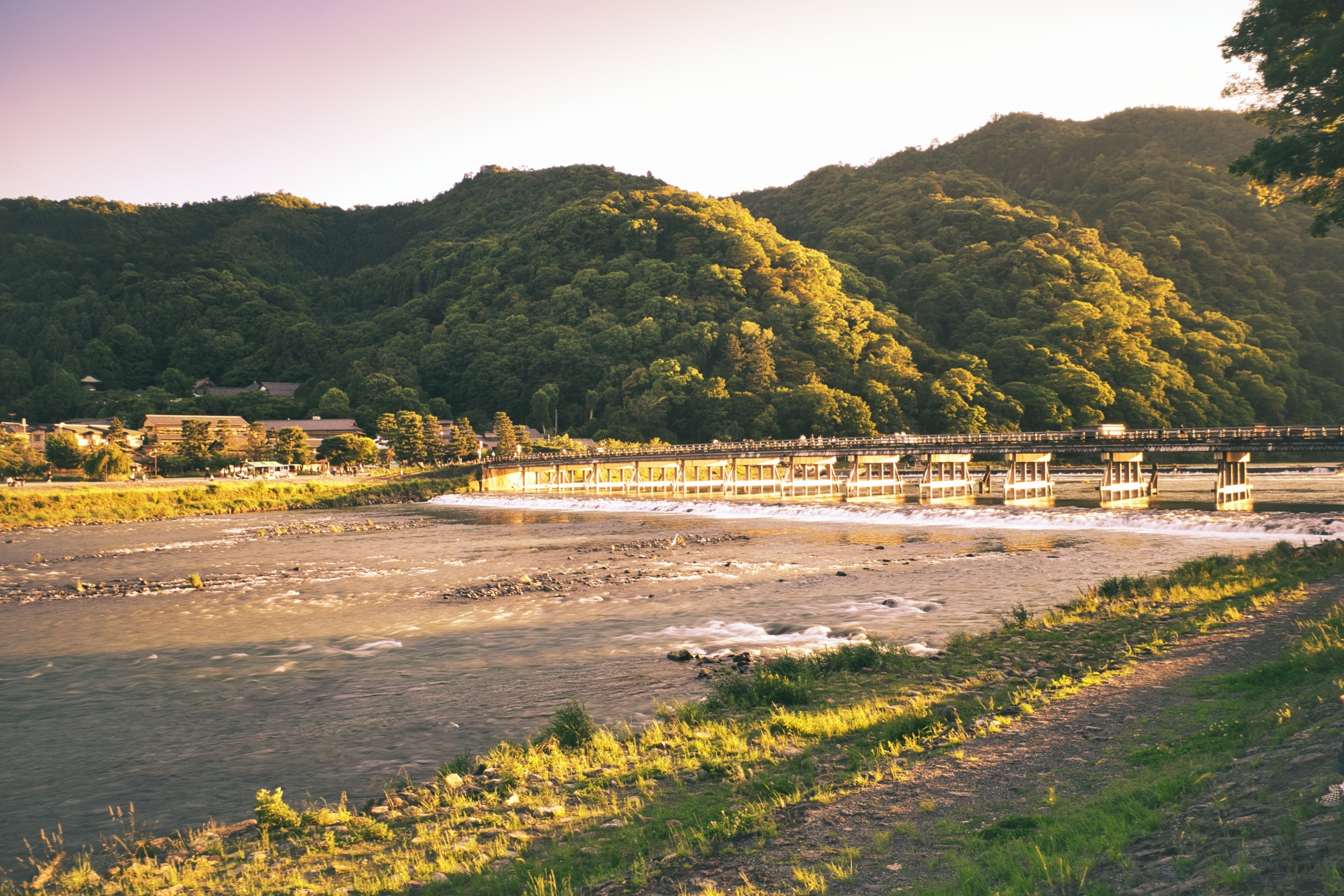 Togetsukyo Bridge over the Hozu River with the Arashiyama mountain ridge behind in warm golden hour light