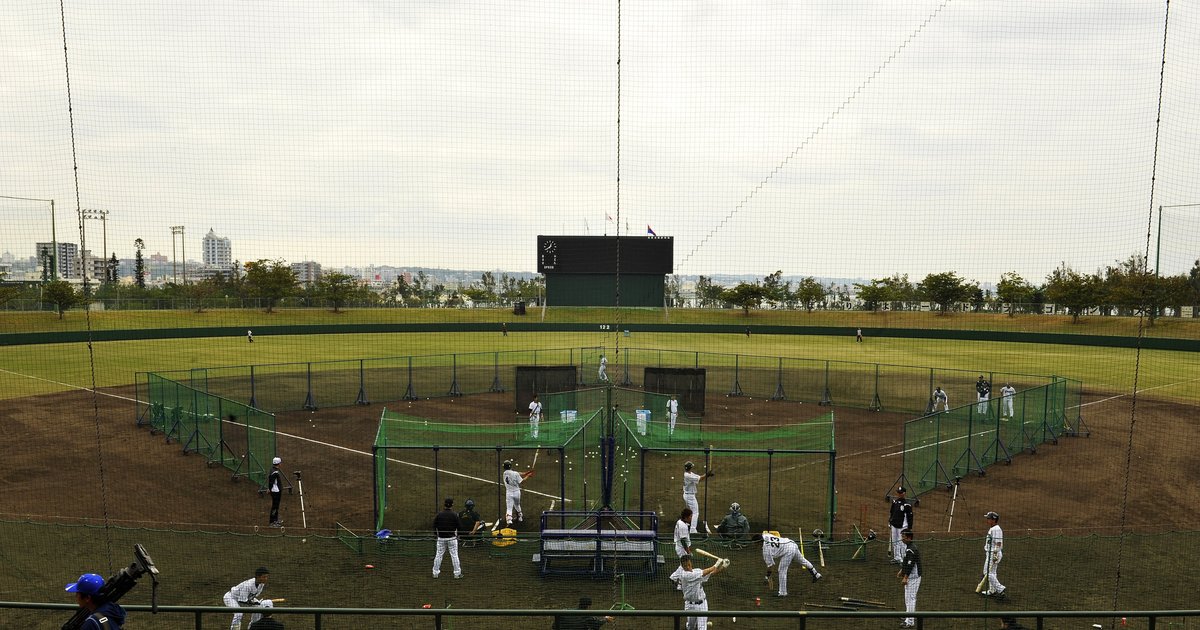 2015 年 2 月沖繩北谷公園野球場的春訓練習:中日球員在內野好幾組綠色打擊籠裡輪流打擊,外野草地與記分板後方是北谷的市街,畫面前方隔著防護網