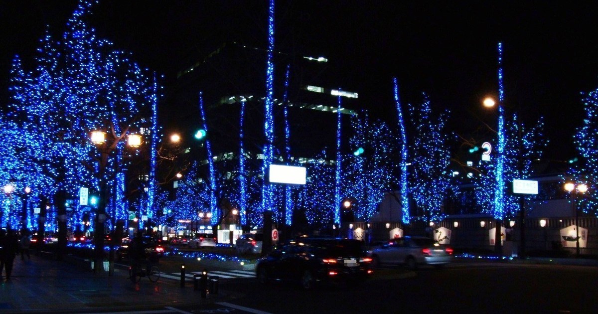 Midosuji boulevard at night, its street trees wrapped in illumination forming a continuous corridor of light down the avenue