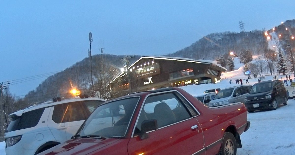 傍晚的さっぽろばんけいスキー場:積雪停車場後方是掛著 ban.K 招牌、窗戶亮燈的木造主建築,右後方山坡雪道的照明燈已經點亮