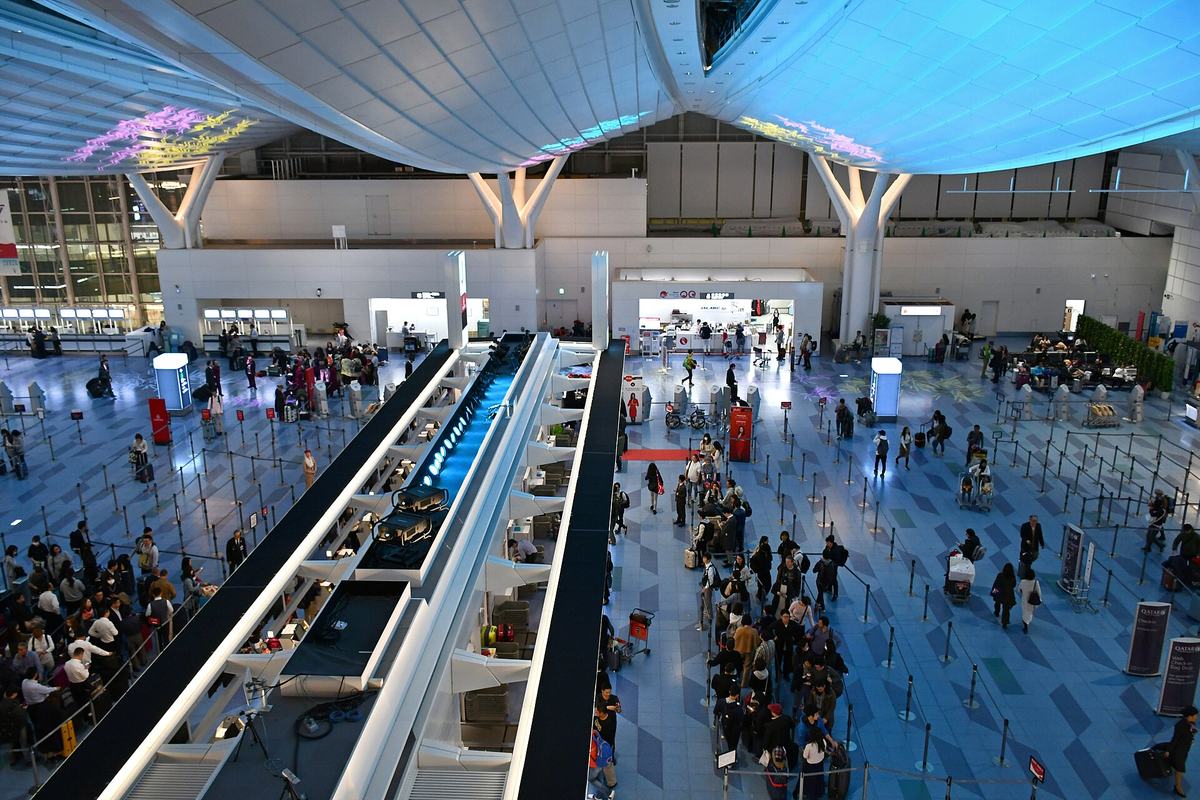 Passengers queueing at an airline service counter in a Japanese airport while ground staff process rebookings