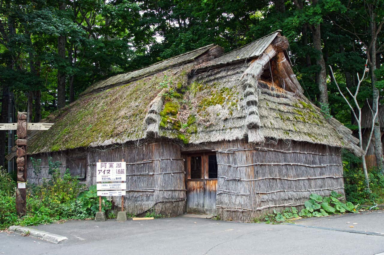 The large wooden owl carving and Ainu craft-shop lane at the entrance to Lake Akan Ainu Kotan