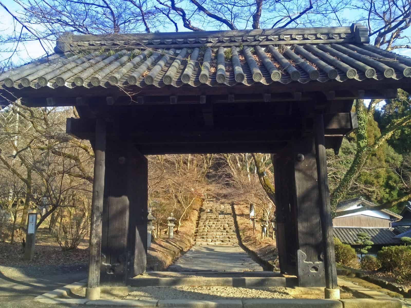 The black wooden Kuromon gate of Akizuki Castle, now the gate of Suiyo Shrine, framed by autumn leaves (illustrative)