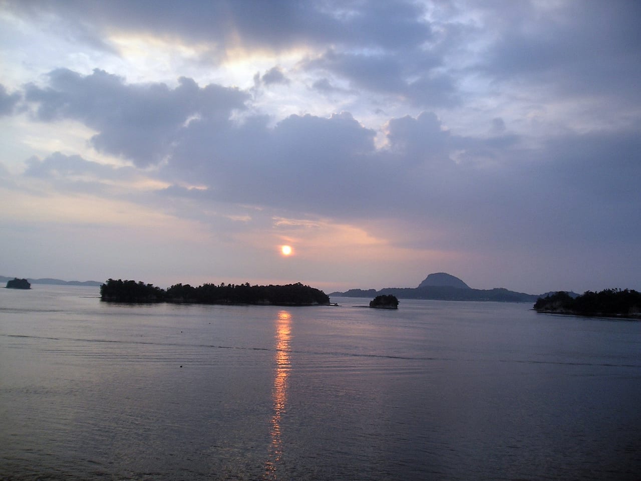 A red-orange sunset sinking into the sea horizon over the Amakusa Five Bridges waters