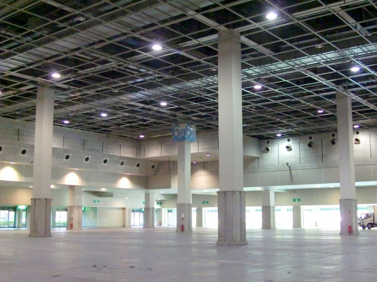 インテックス大阪 6 號館 B 區沒有布展時的內部:挑高的格狀天花板、幾根粗方柱,柱上掛著藍底「6B」標示,地板空無一物