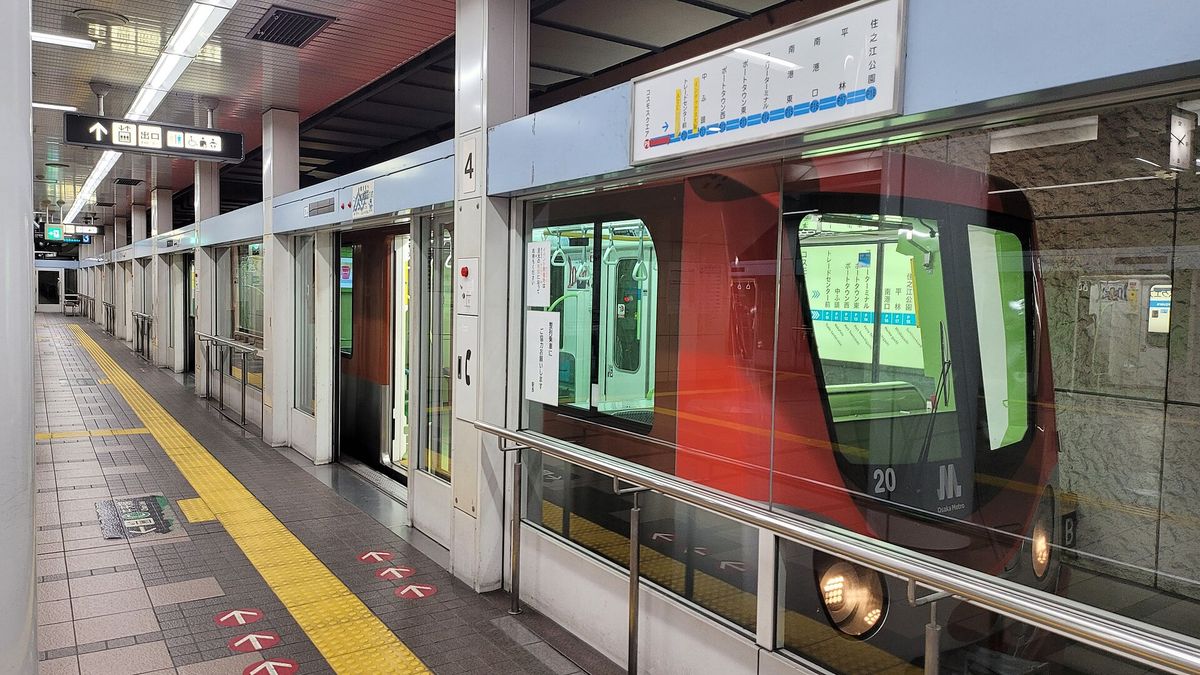 コスモスクエア站ニュートラム 4 號月台:紅色車頭的無人電車停在月台門後,上方路線圖由コスモスクエア往右依序是トレードセンター前、中ふ頭、ポートタウン西,一直到住之江公園
