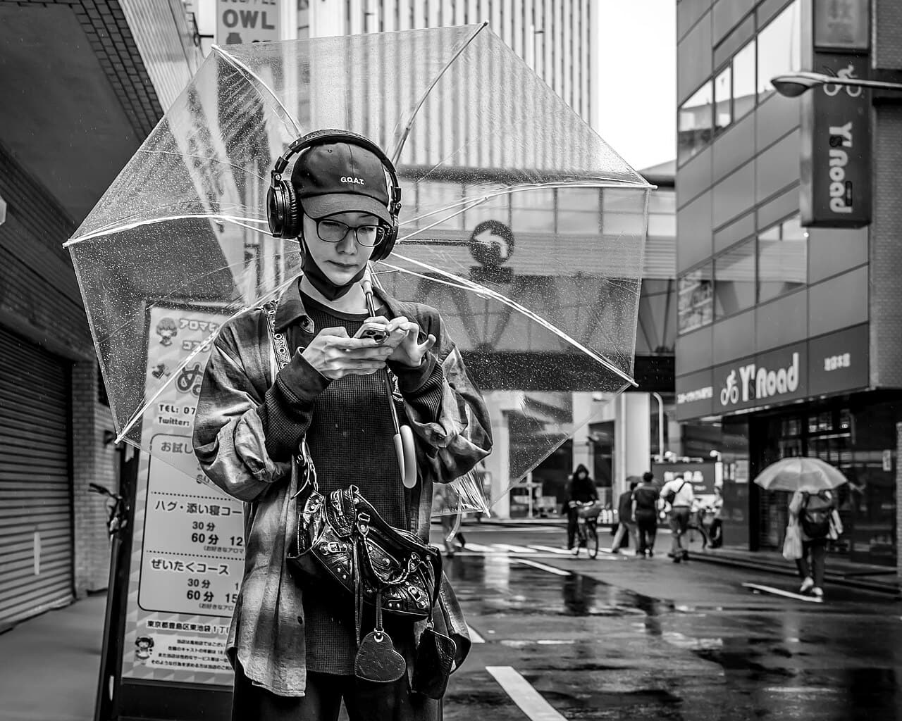 A traveller holding an umbrella and using a smartphone on a Japanese street — translation and maps apps are everyday tools for independent travel