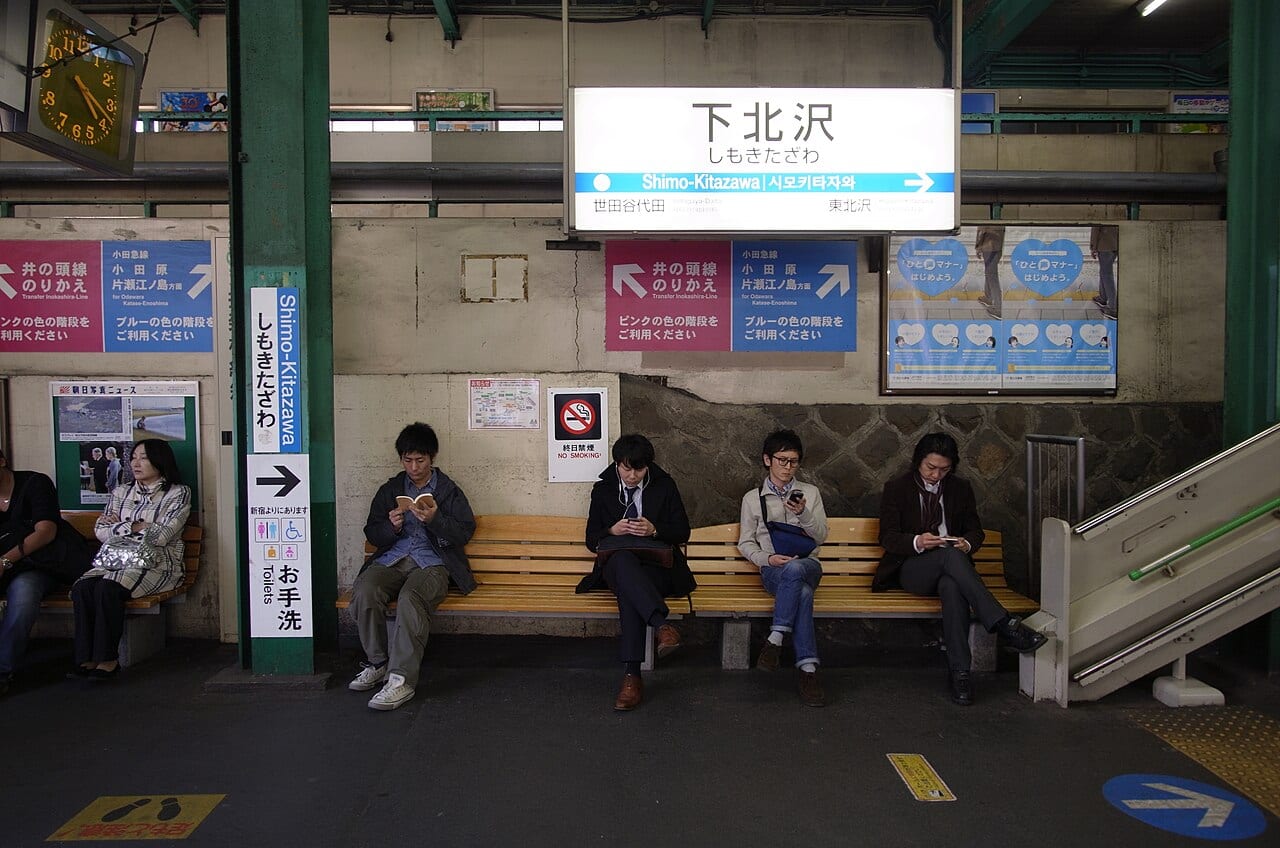 Travellers waiting on a Japanese train platform, where a maps or transit app is the everyday tool for getting around