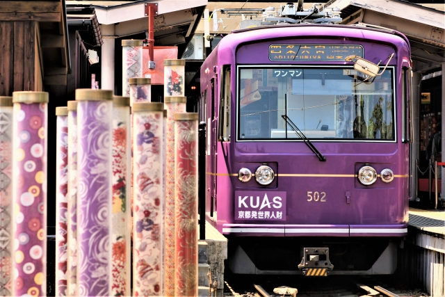 A purple Randen tram pulled up at Arashiyama Station with the lit kimono-pattern lanterns lining the platform