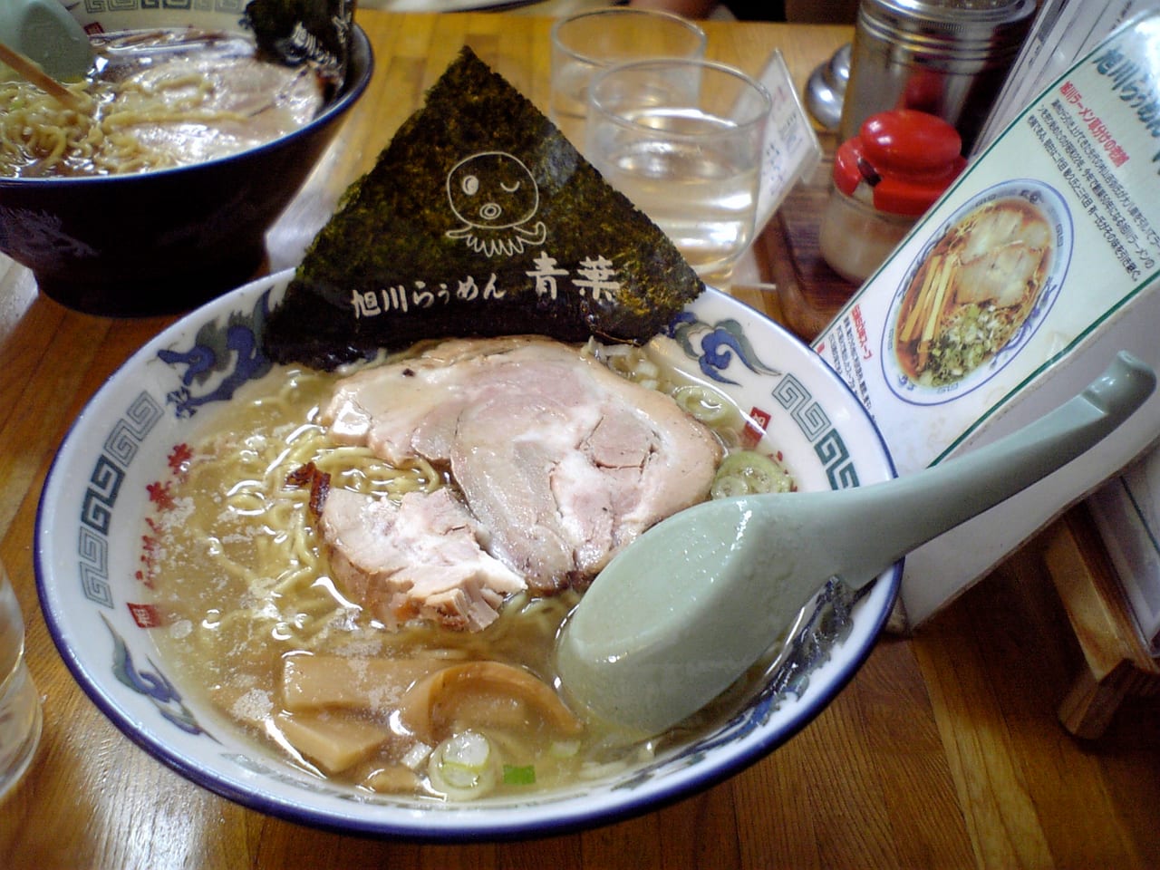 A bowl of Asahikawa soy-sauce ramen with thin curly noodles and lard floating on the broth