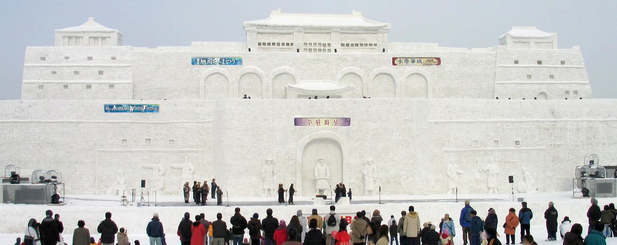 旭川冬祭 2007 年第 48 回的主雪像,仿韓國水原華城的城牆與城樓,掛著旭川冬まつり與水原華城的橫幅,雪像正下方是舞台,前面一排遊客背對鏡頭看表演