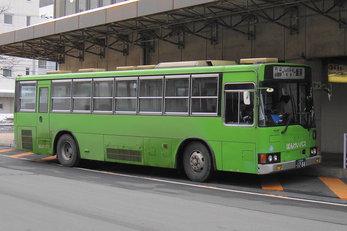 一輛綠色的ばんけいバス停在有鋼骨雨棚的巴士月台旁,車頭方向幕寫著「円山公園駅」「ばんけいスキー場経由」「盤渓」,車頭下方印著「ばんけいバス」