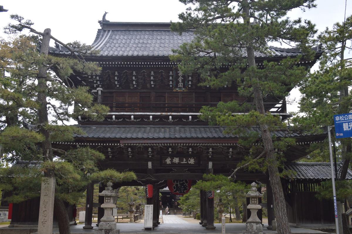 The two-storey Sanmon gate of Chionji temple, stone lanterns and pines in front, a signpost to Kasamatsu Park and the sightseeing boat pier on the right