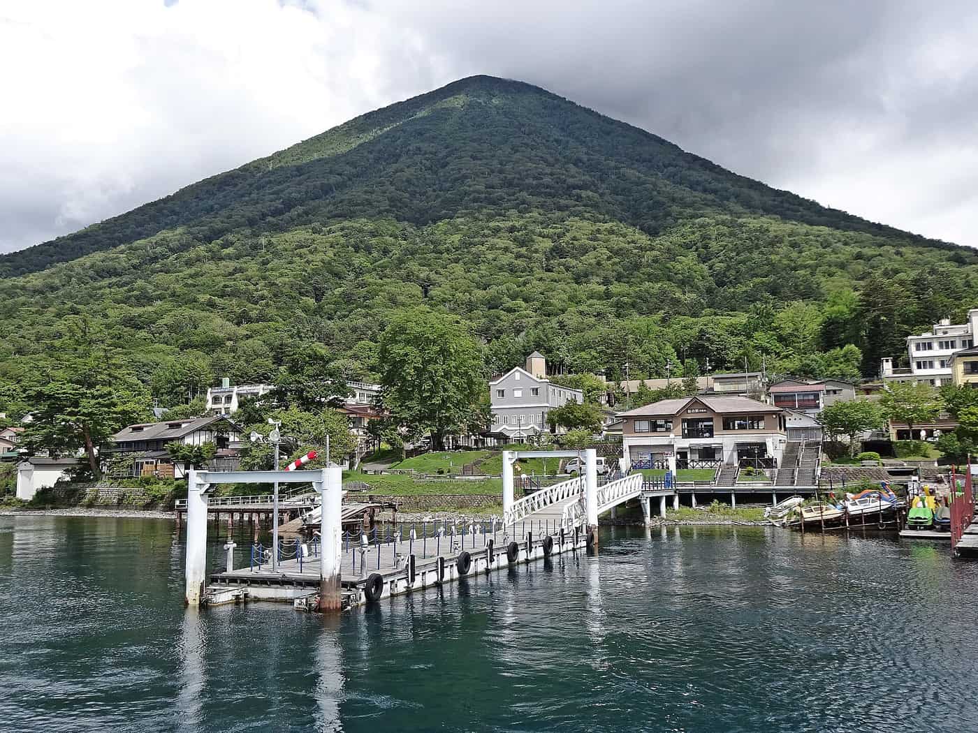 The boarding pier at Funanoeki Chuzenji with the green cone of Mount Nantai rising behind Lake Chuzenji