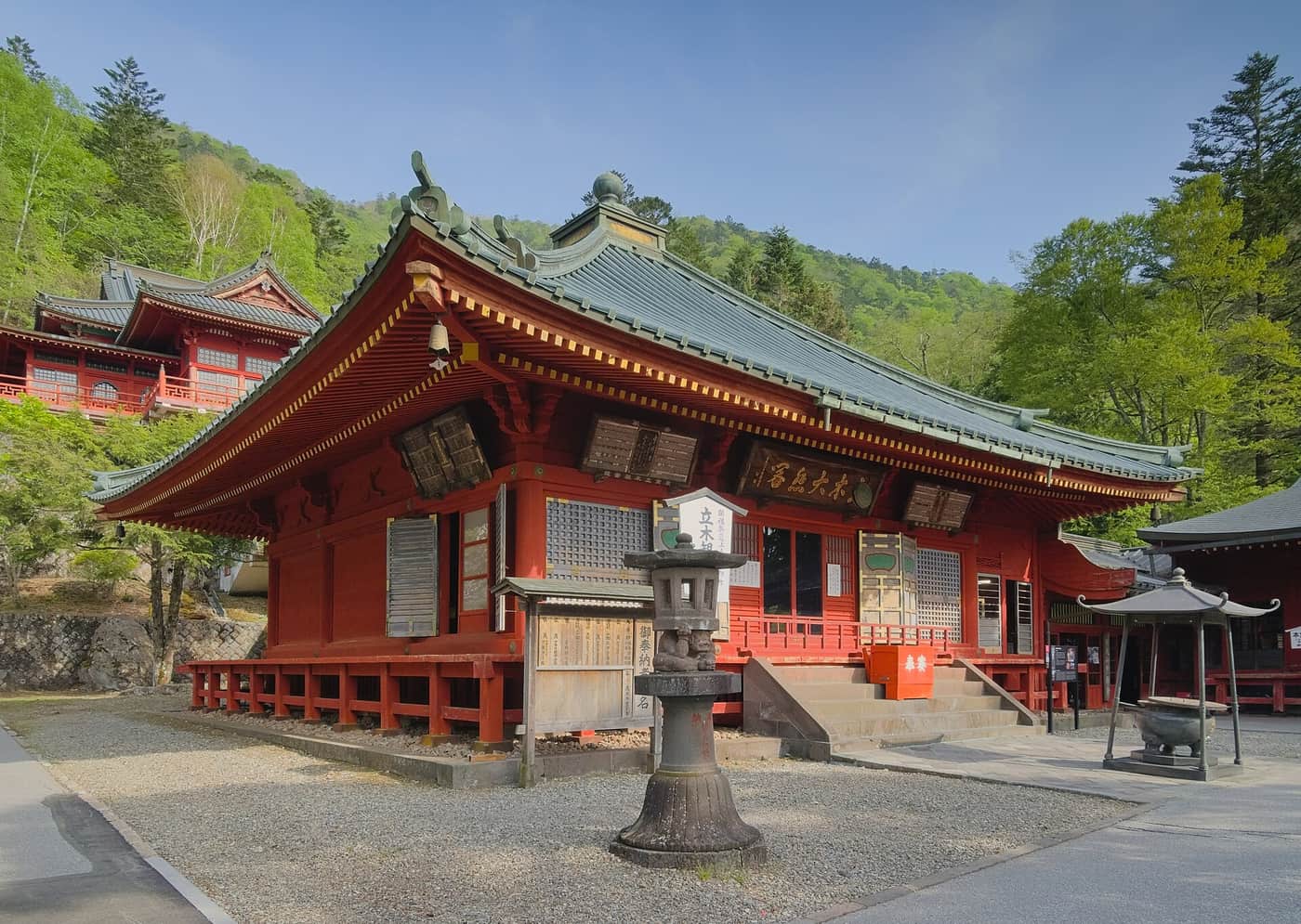 The vermilion main hall of Chuzenji Temple bearing the Tachiki Daihikaku plaque, with the Godaido hall on the slope behind