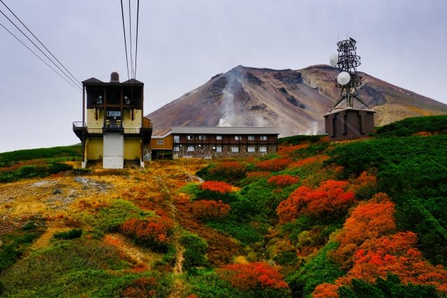北海道大雪山黑岳 9 月下旬紅葉，山頂楓海與遠方殘雪火山口