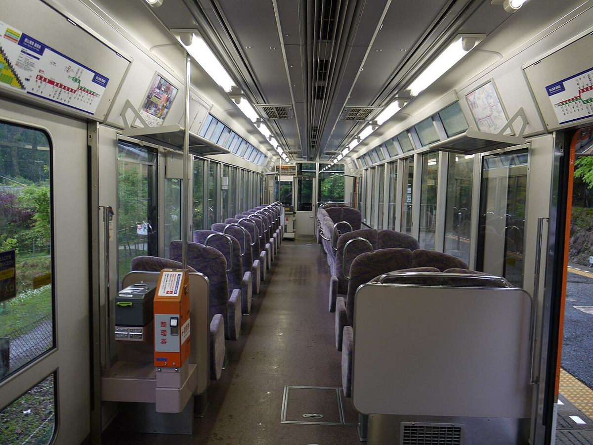 叡山電車展望列車きらら的空車廂：兩側是一整面的大窗，窗戶上方靠車頂處還有一排斜的玻璃，紫色座椅排在走道兩邊，前方有整理券機
