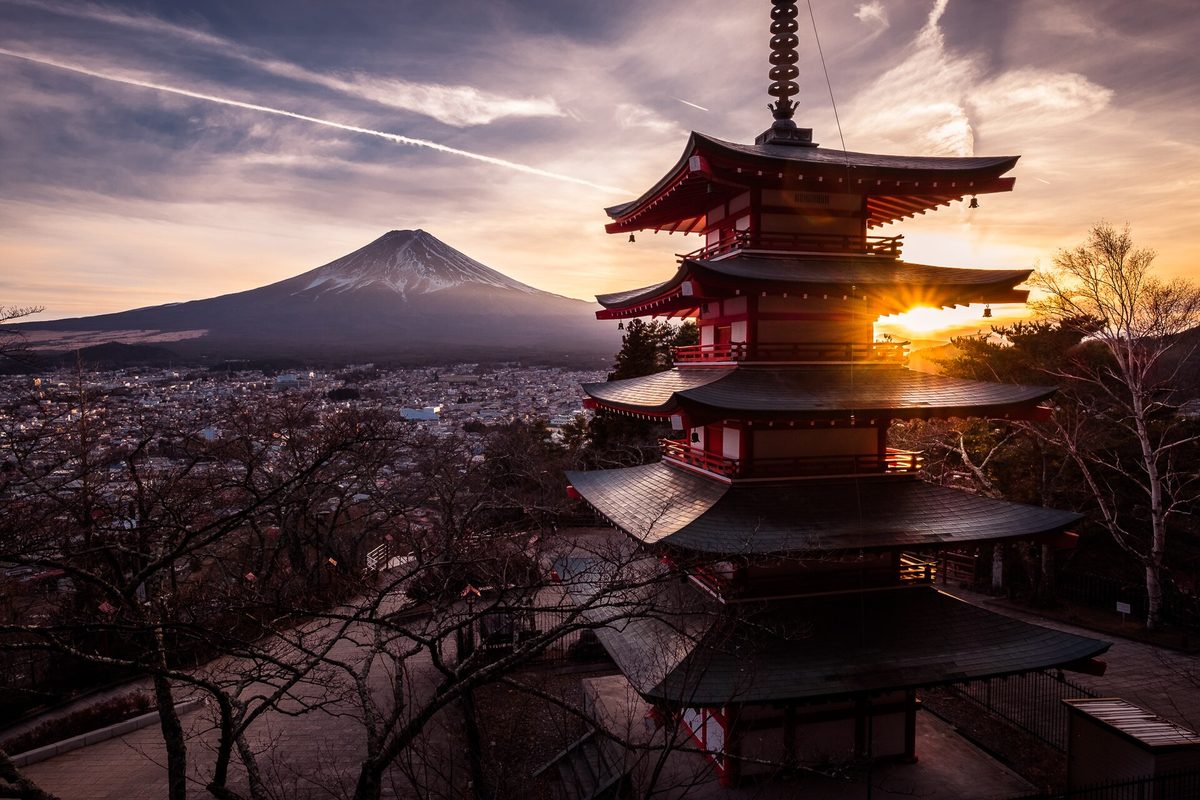 傍晚的新倉山淺間公園:夕陽從五重塔的屋簷後方透出來,左後方是山頂覆著雪的富士山,山下是富士吉田的市街,前景的樹已經落葉