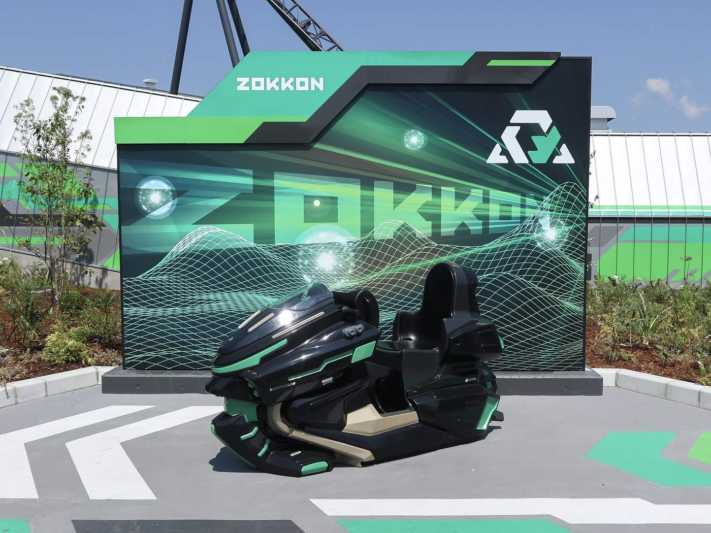 ZOKKON 入口前展示的摩托車型車輛與綠黑配色品牌牆，背景可見軌道支架