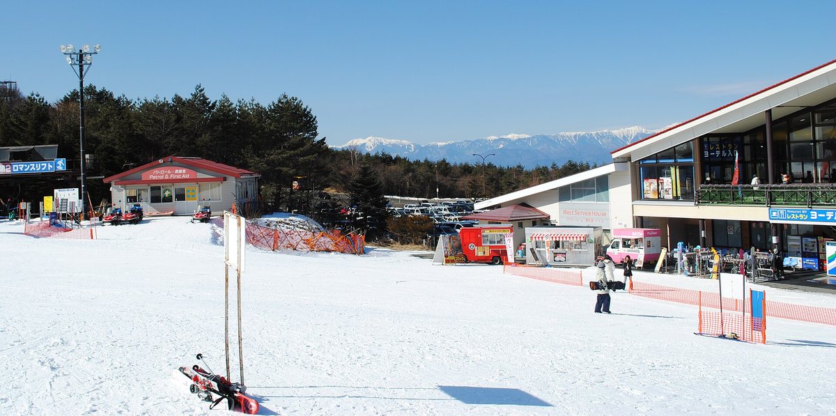 ふじてん滑雪場山麓的服務區：右側是掛著「レストラン」招牌的中心建築，後方停車場停滿車，遠方是積雪的山脈