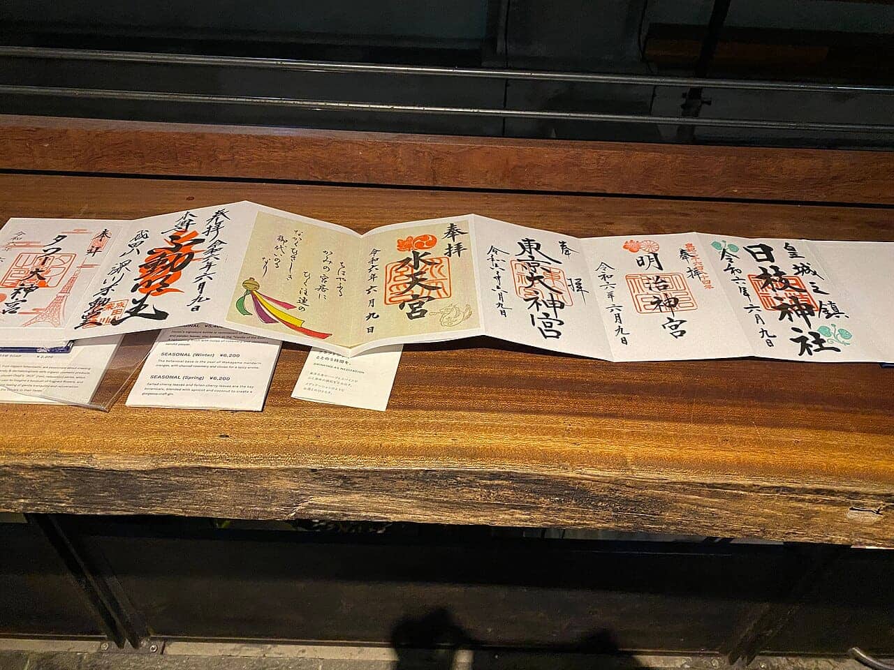 An accordion-fold goshuincho opened flat, showing hand-brushed goshuin from Meiji Jingu, Hie Jinja, Suitengu and other Tokyo shrines