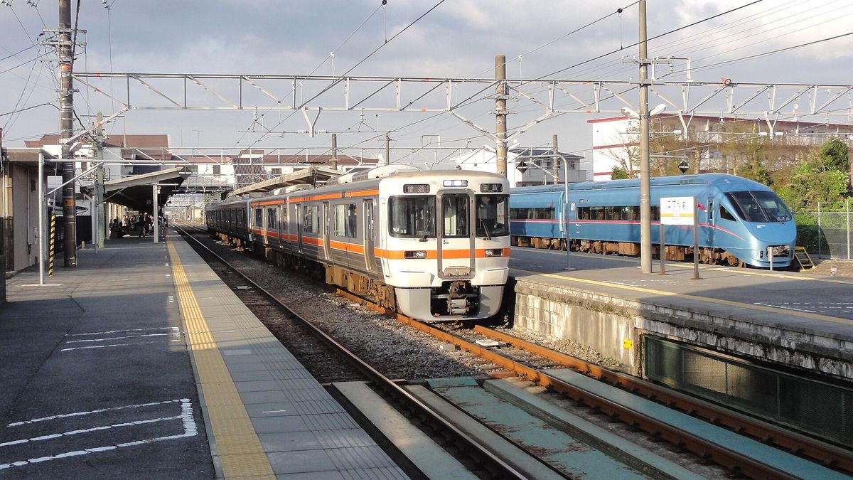御殿場站月台：一列白底橘色腰帶的 JR 電車停在月台邊，右後方的側線停著藍色的小田急特急車廂