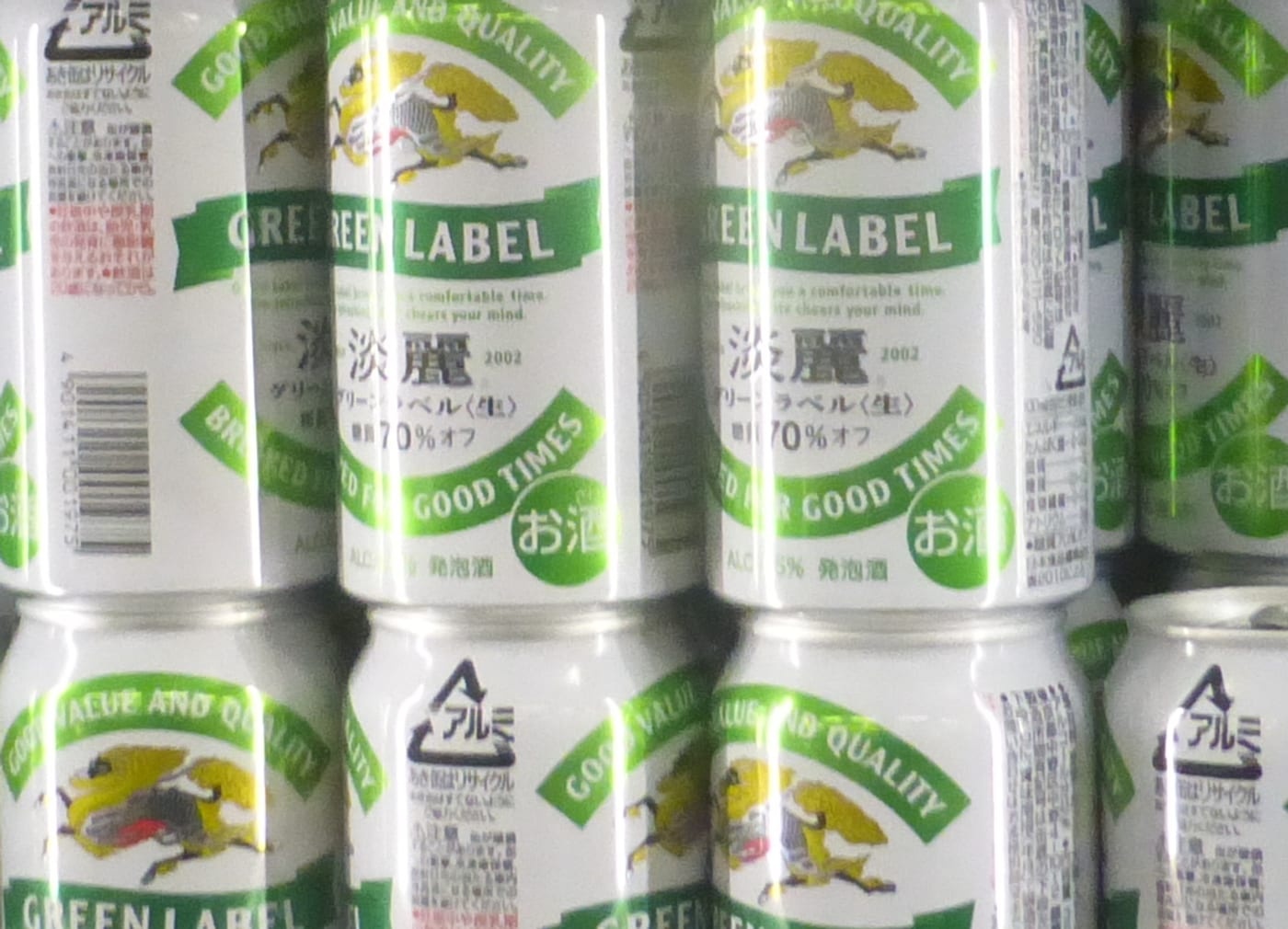Close-up of the category line printed on Japanese cans: white Kirin Tanrei Green Label aluminium cans, with the Japanese brand text below a green ribbon and, along the bottom rim, a small line reading ALC.5.5% happoshu next to a round green Japanese alcohol mark.