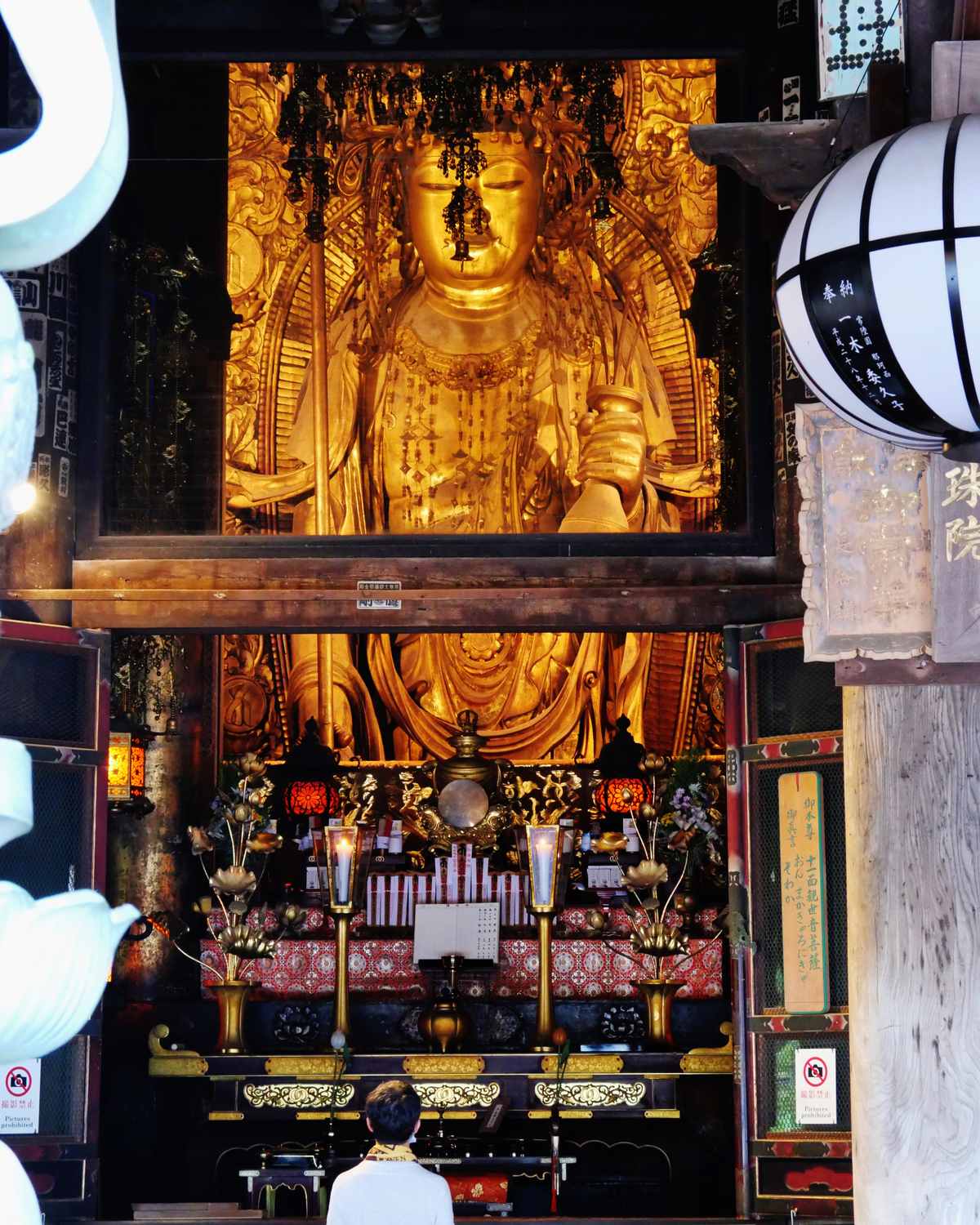 長谷寺本尊十一面觀音金色立像全景,透過本堂格窗仰視,下方參拜者顯出 10 公尺像高的比例