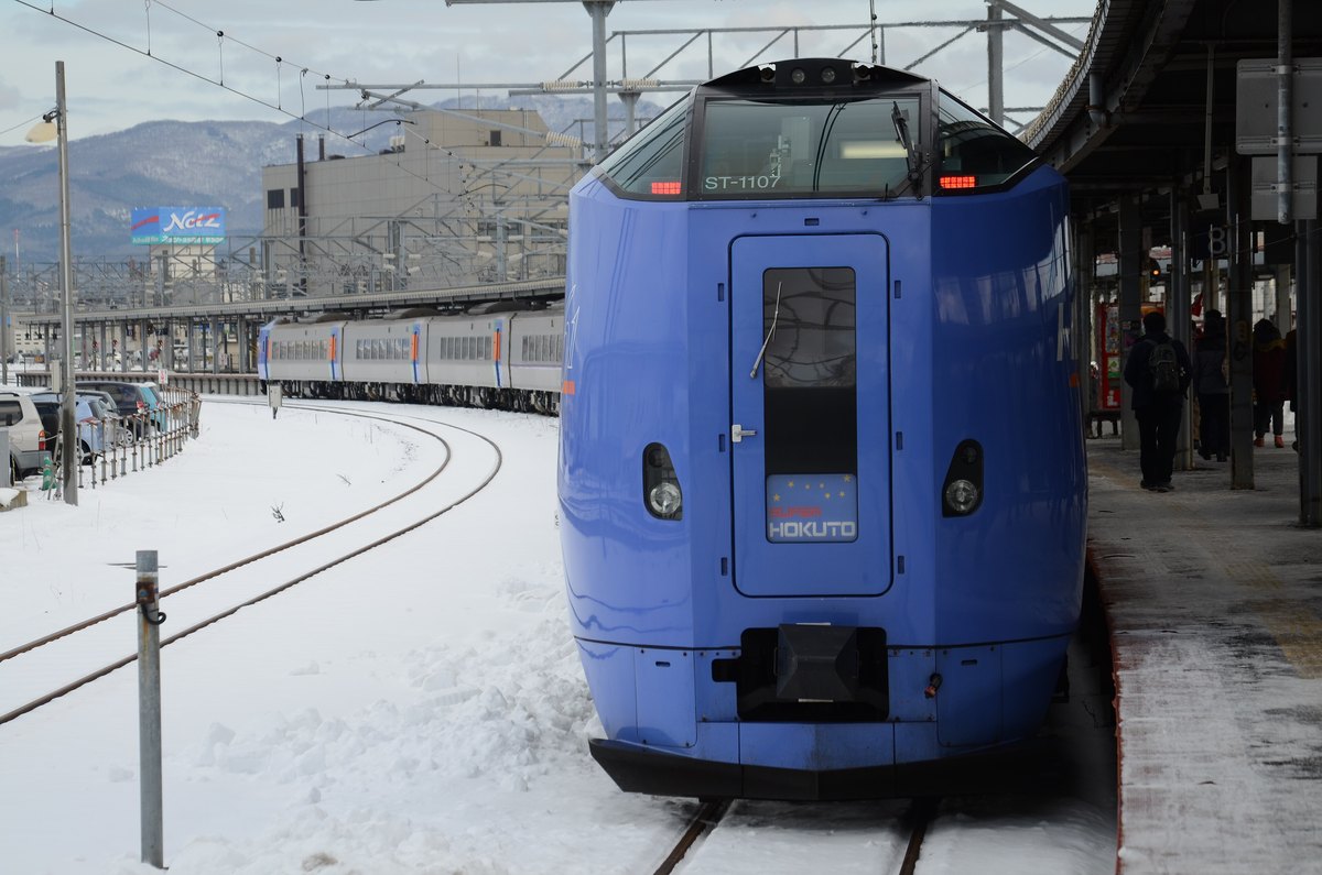 A JR Hokkaido KiHa 261 series Limited Express Super Hokuto standing at a snow-covered platform at Hakodate Station, with snow lying across the tracks