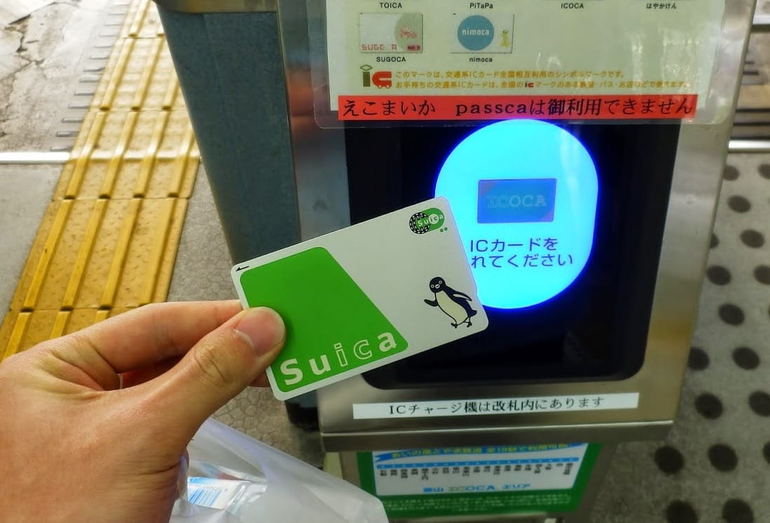 旅客將 Suica IC 卡放在車站閘門感應區嗶卡進站,日本交通 IC 卡最常見的使用畫面