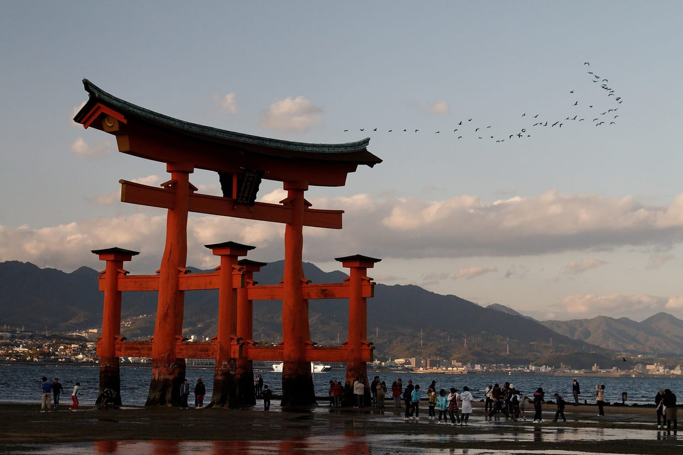 Visitors walking on the exposed tidal flats to the base of the great torii of Itsukushima Shrine at low tide