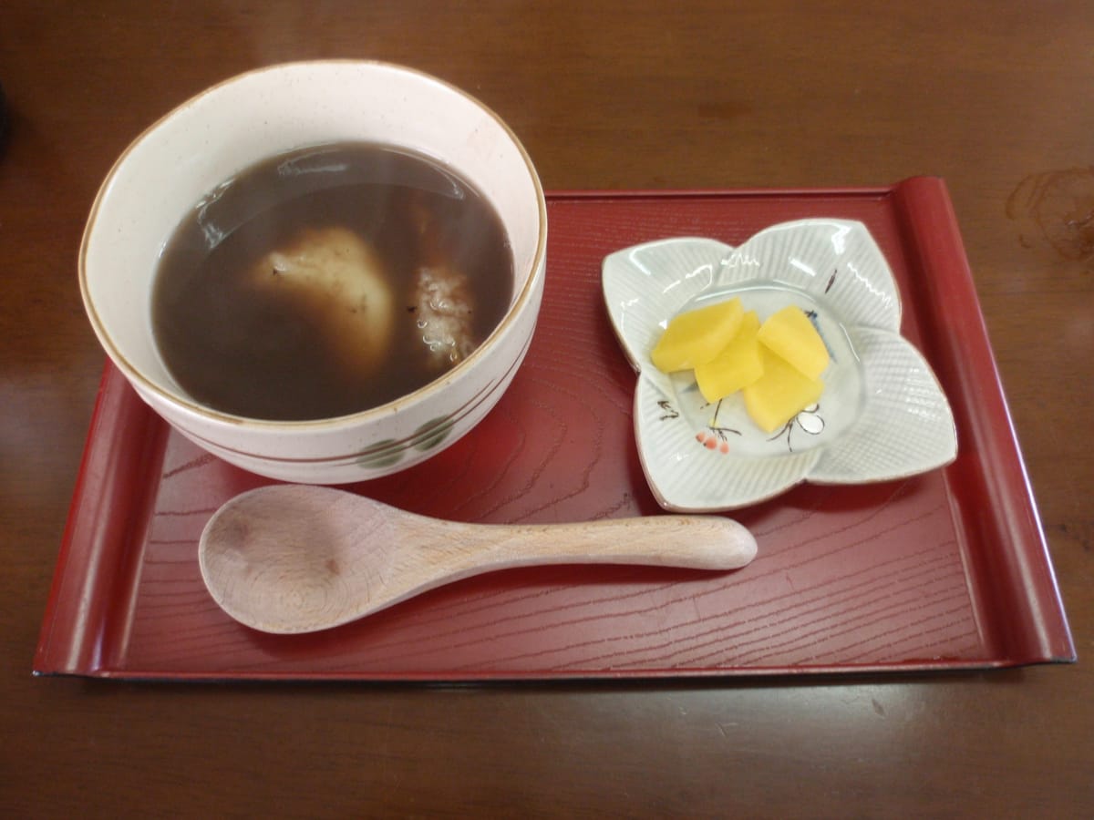 A bowl of Izumo zenzai, sweet red bean soup with round mochi, served with pickles