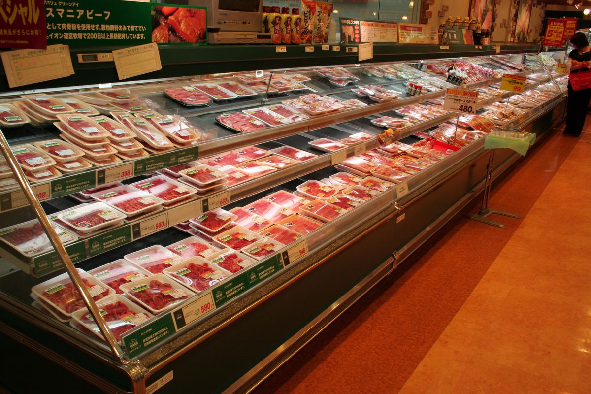 Chilled meat counter in a Japanese supermarket, rows of tray-packed fresh beef and pork with yen price tags