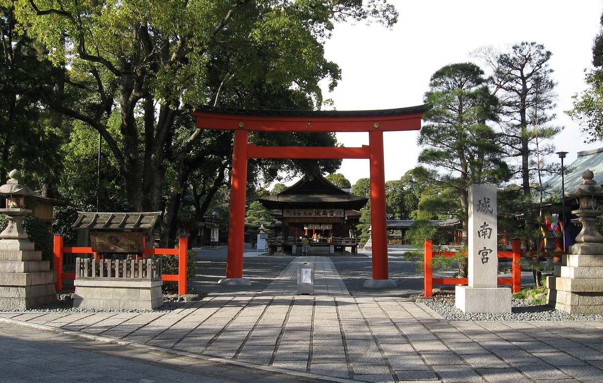 城南宮的朱紅色鳥居:鳥居右側立著刻有「城南宮」三字的石柱,兩旁是石燈籠與朱紅欄杆,石板參道穿過鳥居通往後方的拜殿