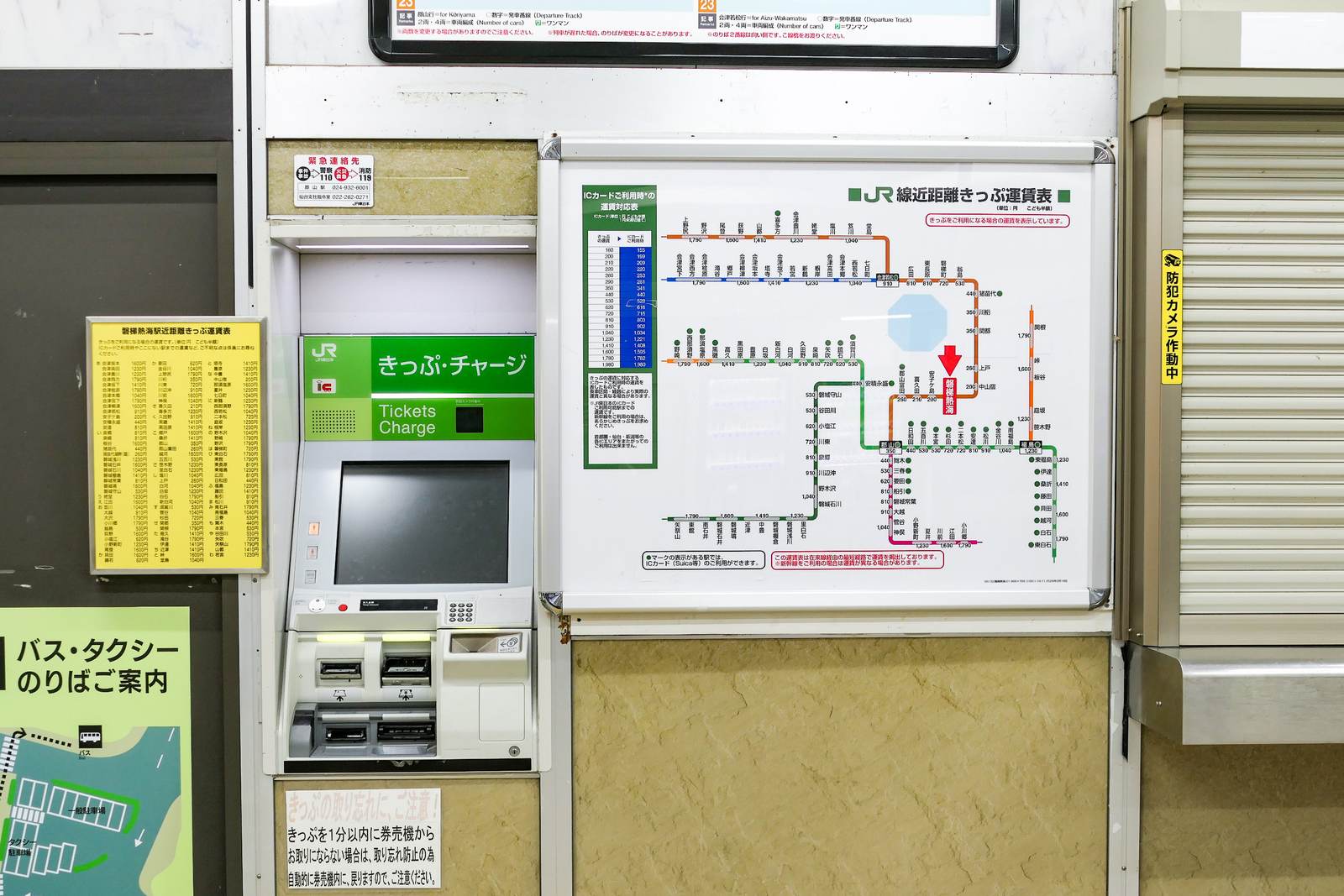 A JR short-distance fare chart mounted on the wall beside a station ticket machine, with a narrow green conversion table to its left whose top row pairs a paper fare of 160 with an IC fare of 155.