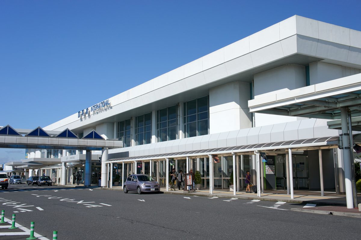 鹿兒島機場國際線航廈外觀,白色建築正面寫著「国際線 INTERNATIONAL」,前方是有頂棚的人行道與車道