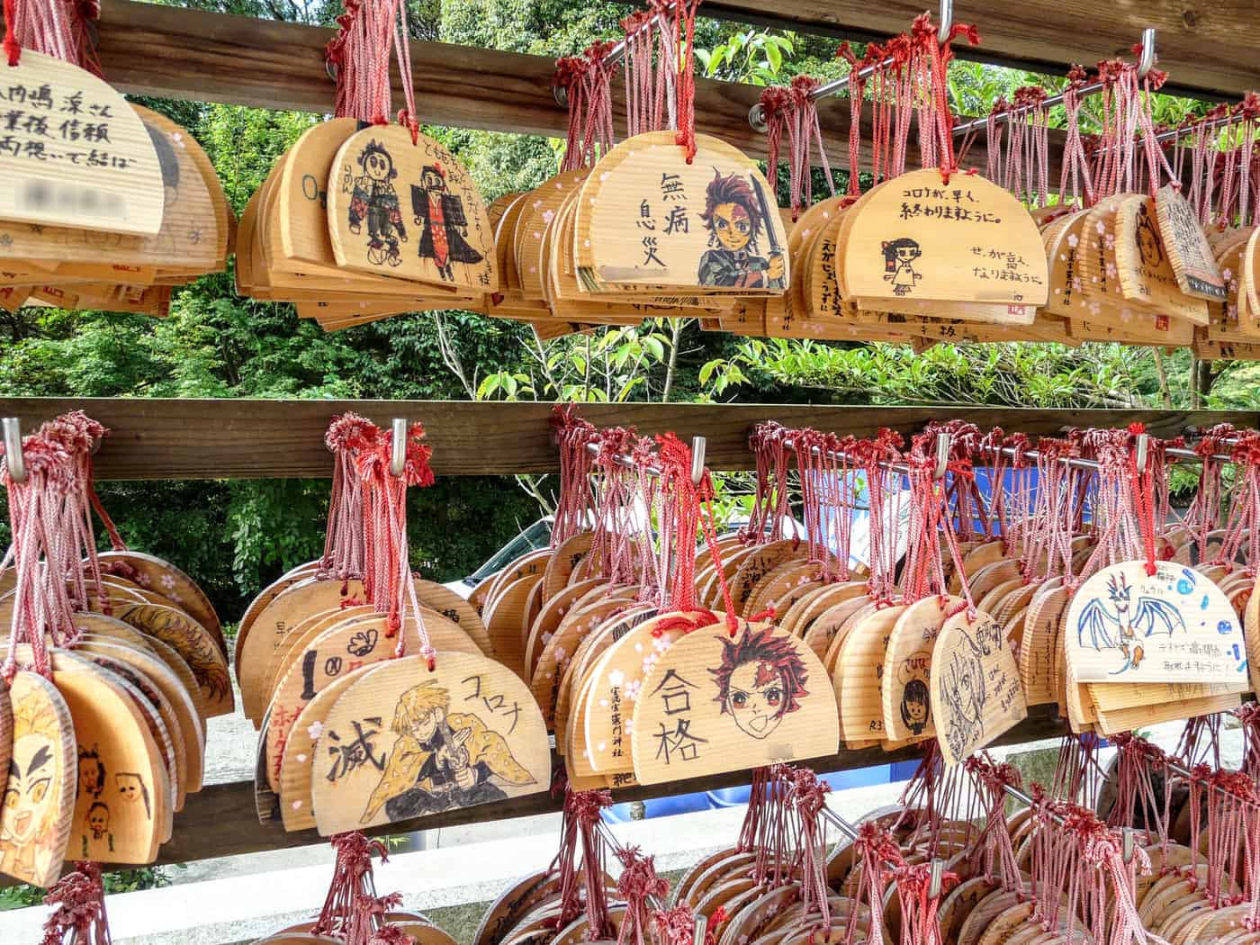 Racks of wooden ema wish plaques hung at Kamado Shrine, densely covered in handwritten wishes