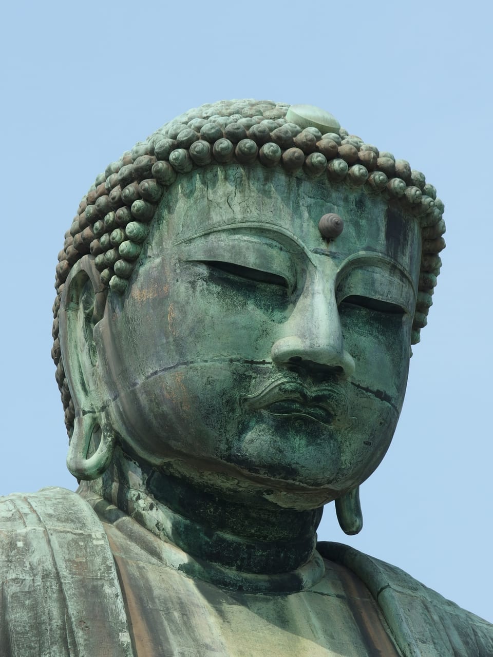 The open-air bronze Great Buddha seated at Kotoku-in temple in Kamakura under a blue sky