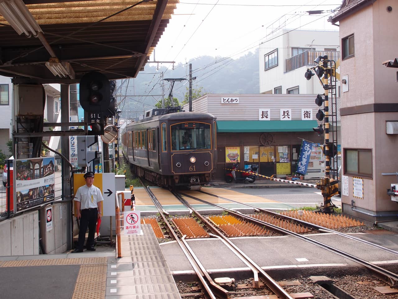 A green Enoden train stopped at the platform of Hase station in Kamakura