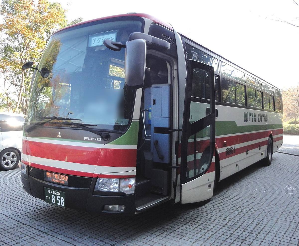 日東交通的アクシー號高速巴士,白底配紅綠條紋的車身,前門打開,擋風玻璃內側上方掛著「アクシー号」的牌子,車側印著 NITTO KOTSU