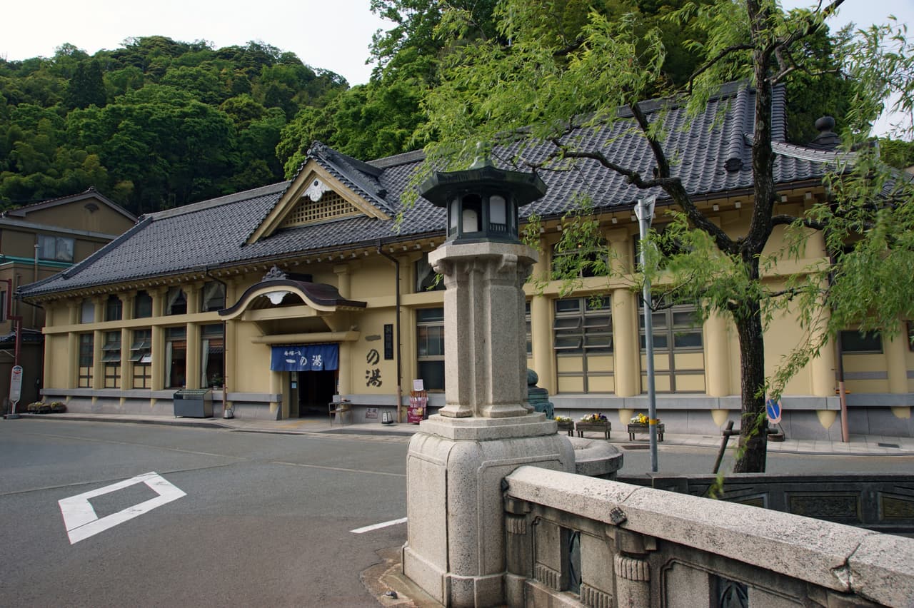 城崎溫泉街的石板路、柳樹與兩側的旅館建築